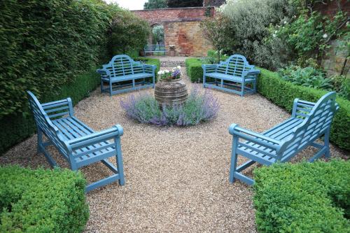 three blue benches in a garden with a fountain at The Manor House Hotel in Moreton in Marsh