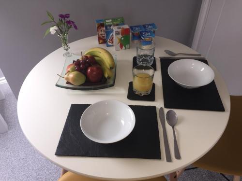 einen weißen Tisch mit einem Obstteller und einem Glas Orangensaft in der Unterkunft Rosenn Teyr in St. Agnes 