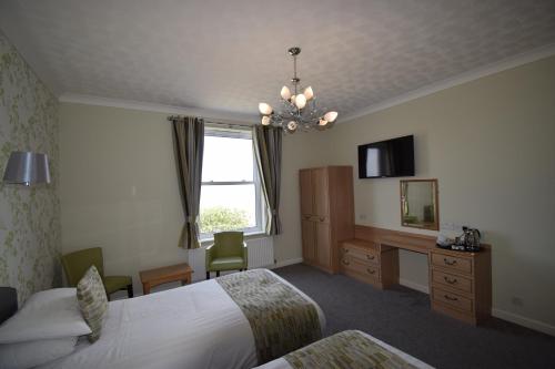 a hotel room with two beds and a desk and a window at The Babbacombe Hotel in Torquay