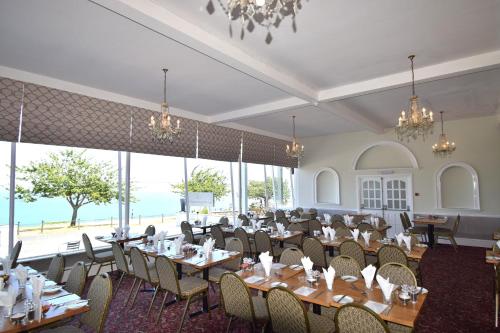 a dining room with tables and chairs and large windows at The Babbacombe Hotel in Torquay