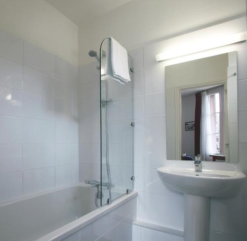 a white bathroom with a sink and a tub and a mirror at Hôtel Ker Izel Saint-Brieuc Centre Historique in Saint-Brieuc