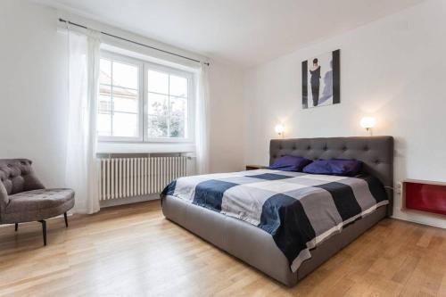 - une chambre avec un grand lit et une chaise dans l'établissement Charmant appartement avec terrasse dans villa, à Strasbourg