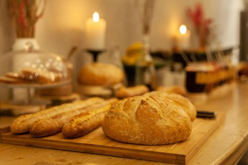 a wooden cutting board with bread and rolls on a table at Hôtel La Nouvelle République & Hammam in Paris