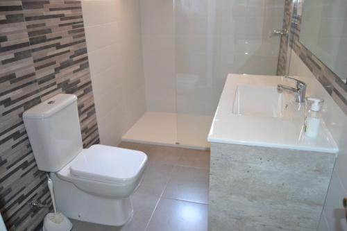 La salle de bains est pourvue de toilettes blanches et d'un lavabo. dans l'établissement Carolina LOCDENIA, à Dénia