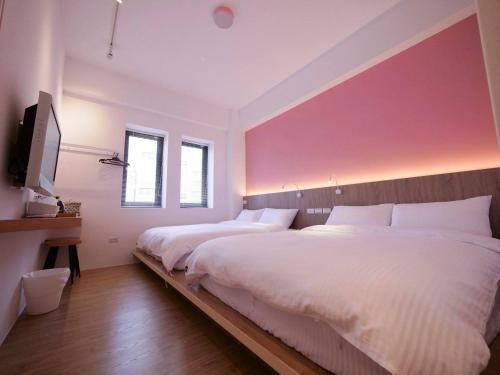 a bedroom with two beds and a pink wall at Miss inn in Magong
