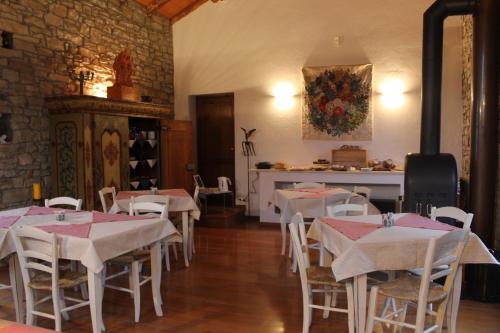 a restaurant with white tables and chairs and a fireplace at Agriturismo La Verena in Vesime