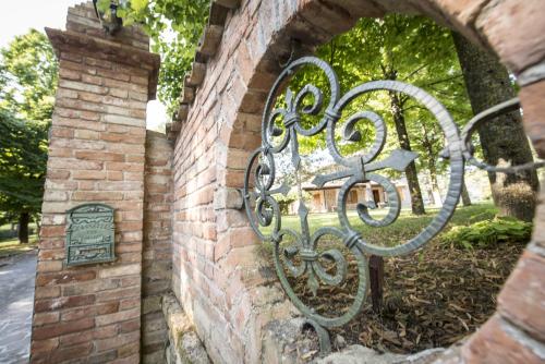 un portail en fer dans un mur de briques avec un panneau dans l'établissement Villa Montegenco, à Comunanza