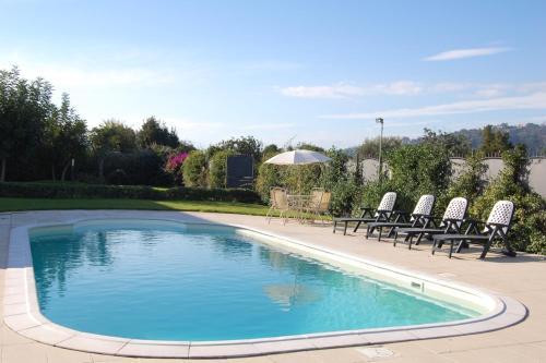 a swimming pool with chairs and a table and an umbrella at Case Vacanze Residence Trinacria in Acireale