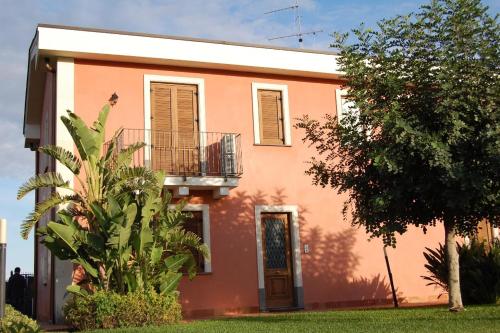 a pink house with a balcony and a tree at Case Vacanze Residence Trinacria in Acireale