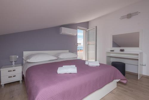 a bedroom with a purple bed with a purple blanket at APARTMANI VUJČIĆ in Makarska