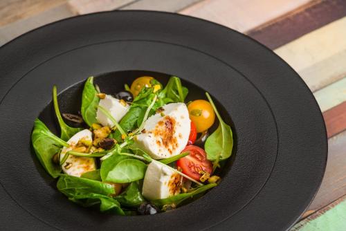 a salad in a black plate on a table at Mercure Budapest City Center in Budapest