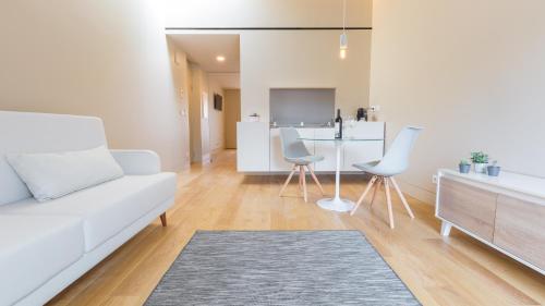 a living room with a white couch and chairs at Braga Heritage Lofts in Braga