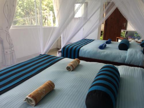 1 dormitorio con 2 camas con sábanas azules y blancas en Sunray Homestay, en Ella