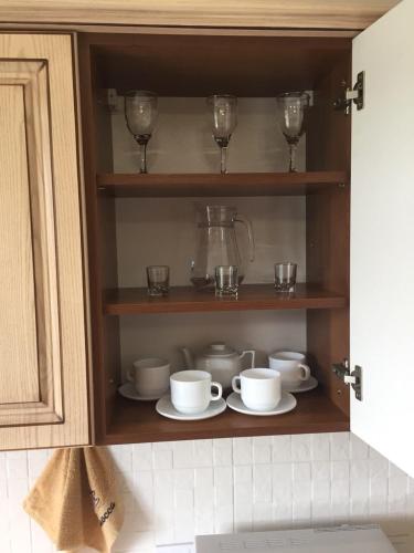 a cabinet with cups and saucers and wine glasses at Polyana Apart in Polyana