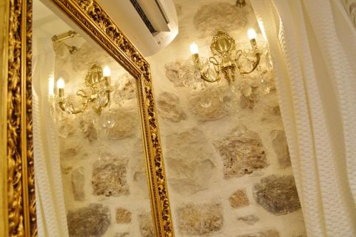 a gold mirror on a stone wall with a chandelier at Villa Madonna della Strada A3 in Dubrovnik