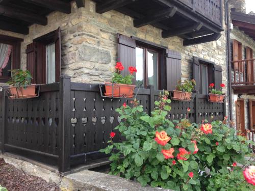 a house with red flowers inpots on a fence at Dimora tra le Alpi - cir n 0004 in Introd