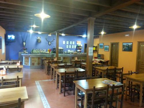 a restaurant with wooden tables and chairs and a bar at Camping Covadonga in Soto de Cangas
