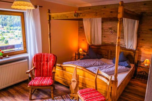 1 dormitorio con cama con dosel y silla roja en Gästehaus Riedl, en Warmensteinach