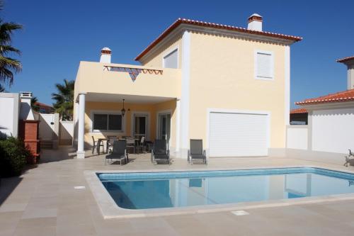 a villa with a swimming pool in front of a house at Praia Del Rei Private Pool Beach Golf in Amoreira