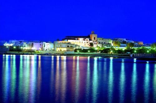 a city lit up at night with a large body of water at B&B PALAZZO MARZO in Otranto