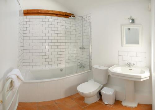 a white bathroom with a toilet and a sink at The Dairy Cottage in Aldeburgh