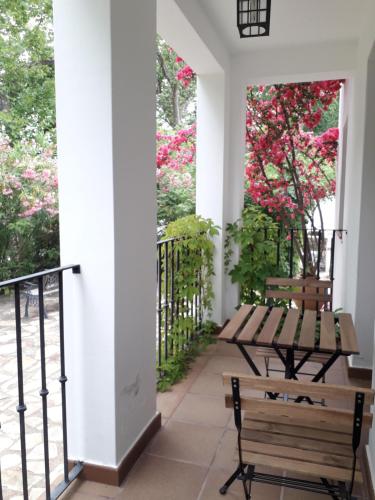 a porch with two benches and pink flowers at Apartamento Rural Las Palmeras in Almonaster la Real