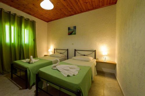2 Betten in einem Zimmer mit grünen Vorhängen in der Unterkunft Villa Fantasea in Plimmiri