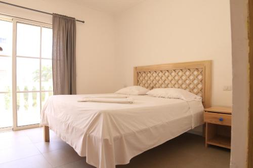 a bedroom with a large white bed with a window at Residencial Las Estrellas in Boca Chica