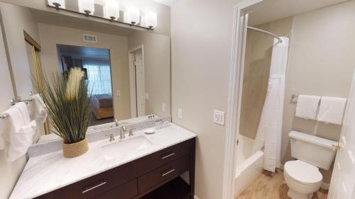 a bathroom with a sink and a toilet and a mirror at Chase Suite Hotel Newark Fremont in Newark