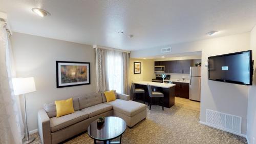 a living room with a couch and a kitchen at Chase Suite Hotel Newark Fremont in Newark