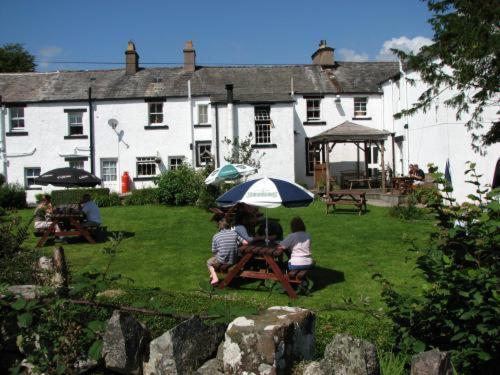 two people sitting at a picnic table under an umbrella at Strands Hotel/Screes Inn & Micro Brewery in Nether Wasdale