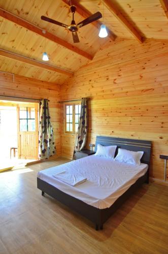 a bedroom with a bed in a wooden room at Cozywoods Hill Resort in Banastarim