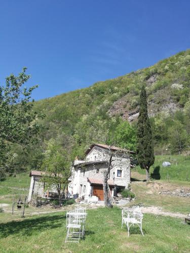 an old house in a field with chairs in front of it at Agriturismo di là dall'Acqua in Fivizzano