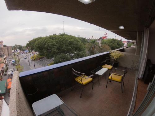 a balcony with chairs and tables and a view of a city at Suites Las Plazas in Cuernavaca
