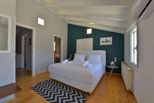 a bedroom with a white bed and a green wall at Villa PortoMare in Porto Rafti