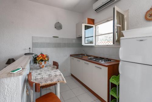 a kitchen with a table and a white refrigerator at Casale Gli Ulivi in Orbetello