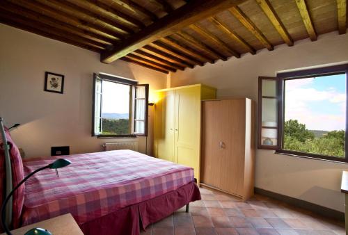 a bedroom with a bed and two windows at Podere Il Pino in Poggibonsi