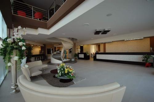 a large room with a lobby with white furniture and flowers at Mediterraneo Palace Hotel in Amantea