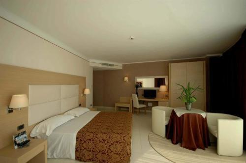 ein Hotelzimmer mit einem großen Bett und einem Schreibtisch in der Unterkunft Mediterraneo Palace Hotel in Amantea