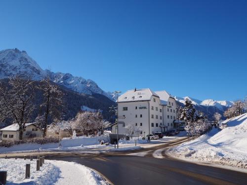 un edificio al lado de una carretera en la nieve en Typically Swiss Hotel Altana, en Scuol