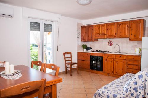 a kitchen with wooden cabinets and a table and a dining room at Case Vacanza Torre Canne in Torre Canne
