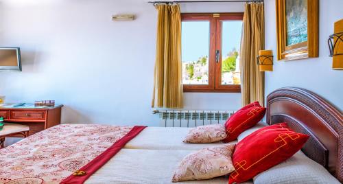 a bedroom with a bed with red pillows and a window at Hotel Mirador Arabeluj in Granada