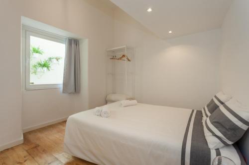 ein weißes Schlafzimmer mit einem Bett und einem Fenster in der Unterkunft BeGuest Santa Catarina Lisbon Apartment in Lissabon