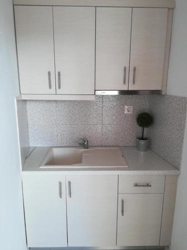 a white kitchen with a sink and white cabinets at Vaya Zorba Studios in Skiathos Town