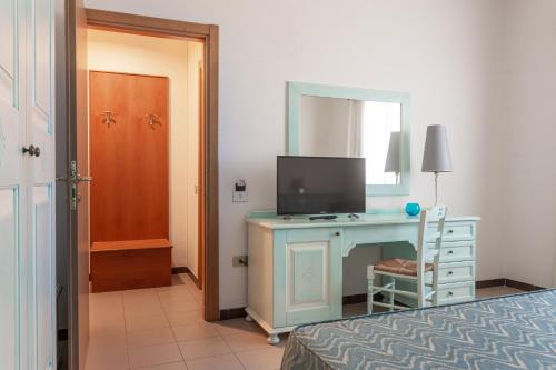 a bedroom with a desk with a tv and a mirror at Rodia Inn in Oristano
