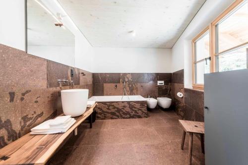 a bathroom with two sinks and a tub and two toilets at Obersteinerhof in Collalbo