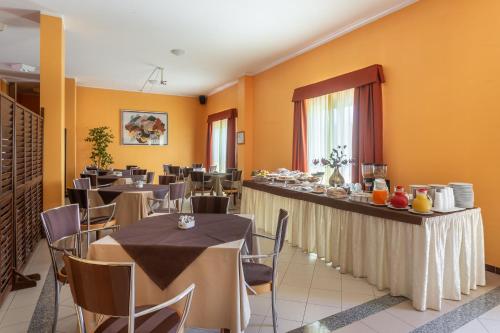 a restaurant with tables and chairs and a buffet at Rodia Inn in Oristano