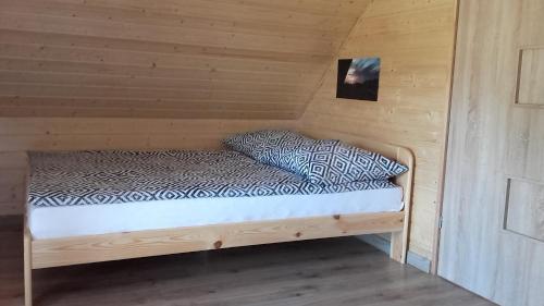 a bed in a room with a wooden wall at Czarcie Chatki in Gardna Wielka