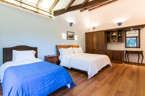 two beds in a room with wooden floors at La Casa Del Arbol Hotel Boutique Villa de Leyva in Villa de Leyva