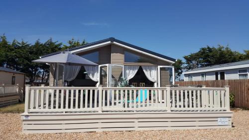 a house with a white fence and an umbrella at Southsea, Beach and Beauty Lodges in Portsmouth